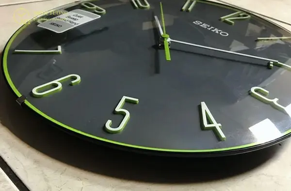 Mặt số đồng hồ bằng nhựa gắn chữ số nổi.